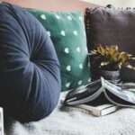 Two books beside three assorted color pillows
