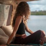 Woman wearing black spaghetti strap top sitting viewing body of water